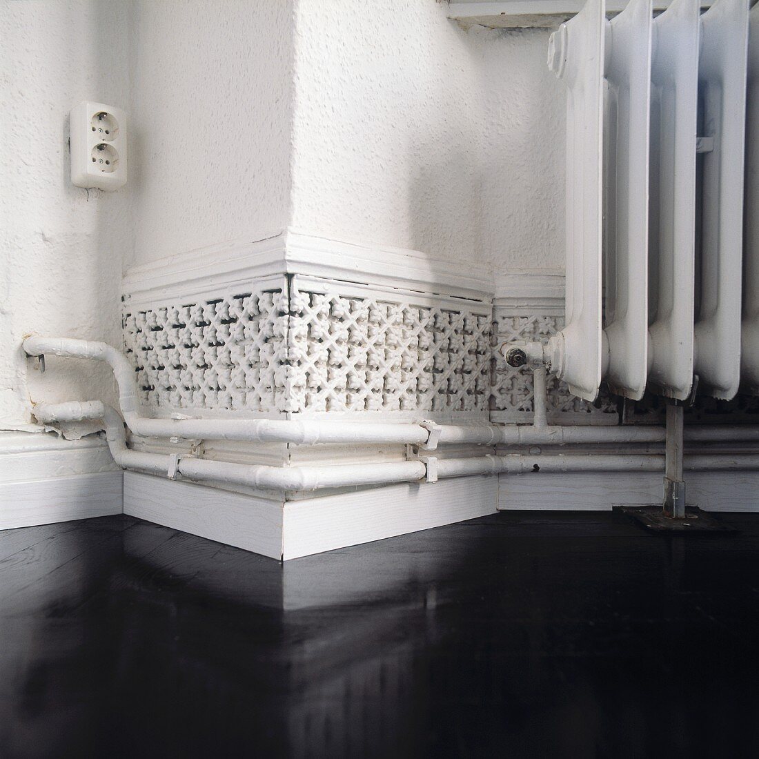 Detail of corner with radiator and ventilation duct with ornamental cover