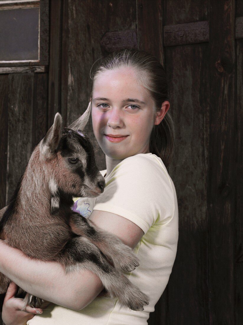 A girl holding a kid goat