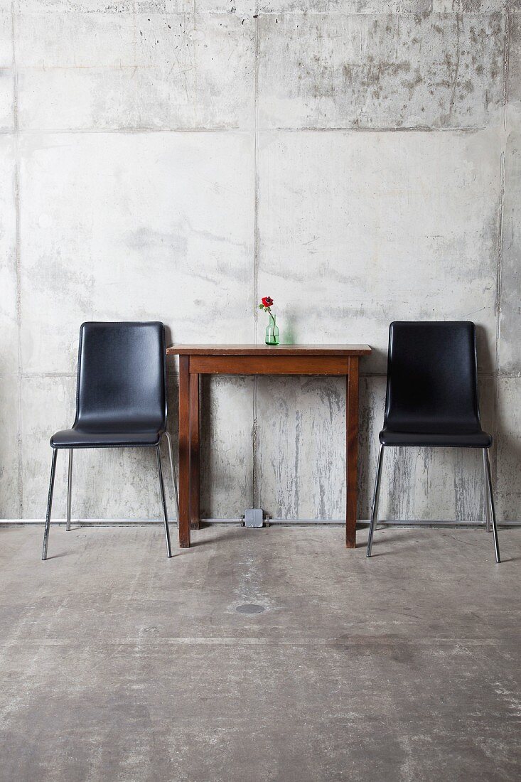 Zwei Stühle und ein Tisch vor Betonwand