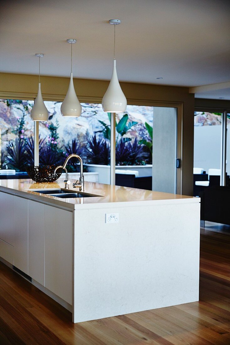 Central island with sink and pendant lamps in modern kitchen
