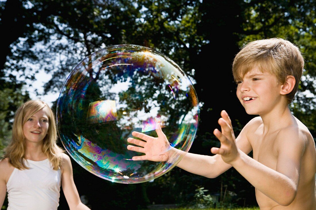 Two children trying to catch a bubble