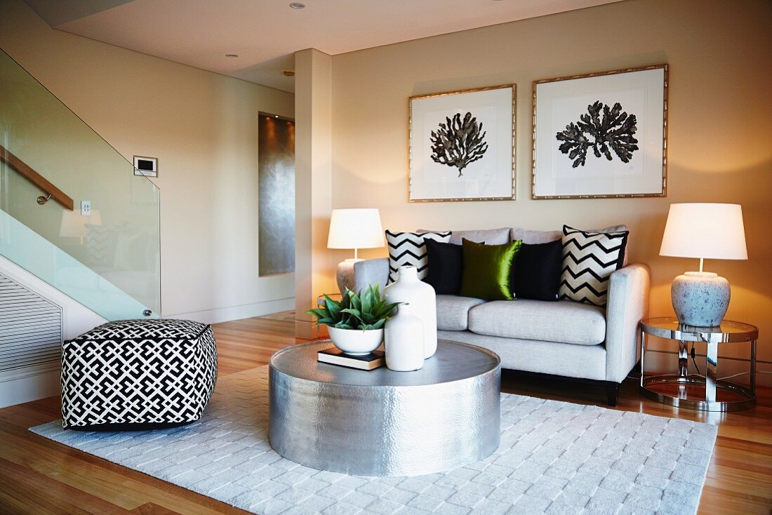 Moderne Lounge mit Sofa, Hocker, Teppich, Metalltisch und Beistelltischen mit Lampen