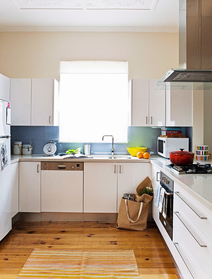 weiße, funktionale Küche mit rustikalem Parkettboden