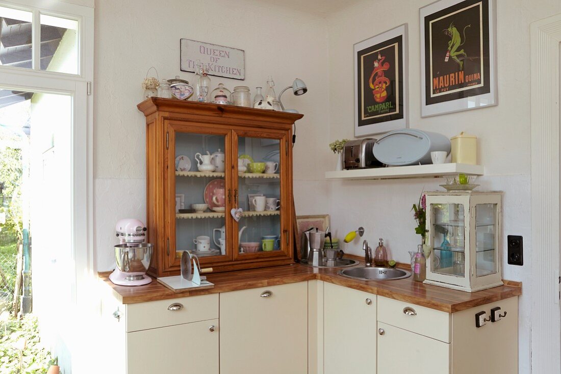 Küche mit kleinen Vitrinen auf Holz Arbeitsplatte, darunter Unterschränke mit cremefarbenen Fronten