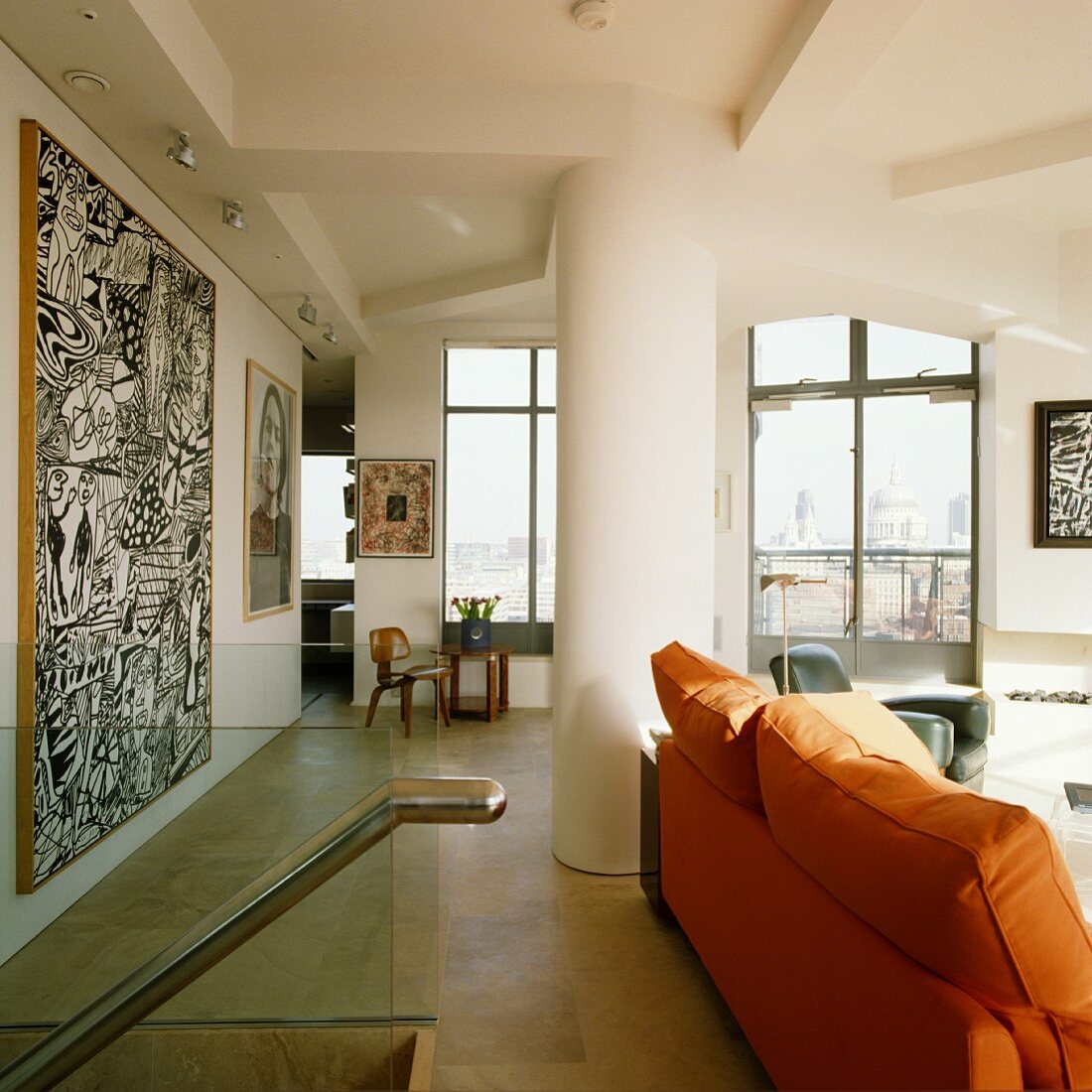 Sofa mit orangefarbener Polsterung vor moderner Kunst an der Wand im Wohnzimmer einer Penthouse-Wohnung mit raumhohen Fenstern