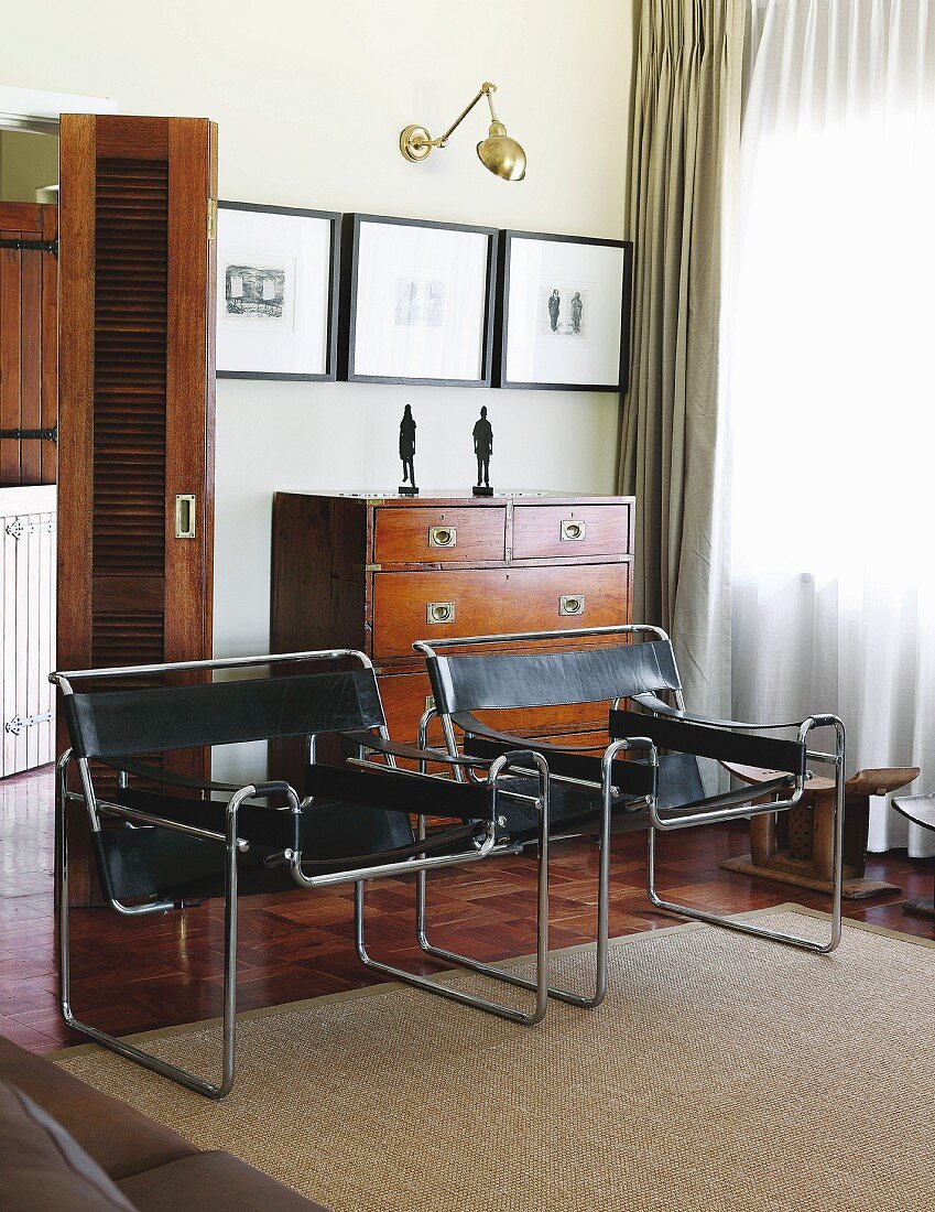 Wassily Stühle mit schwarzem Lederbezug vor Kommode und offenem Durchgang in traditioneller Wohnzimmerecke