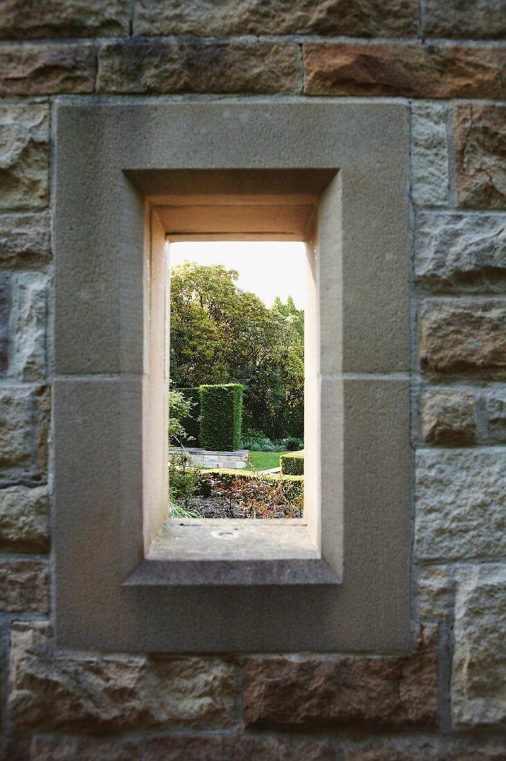 Fensteröffnung mit Gartenblick in Natursteinmauer
