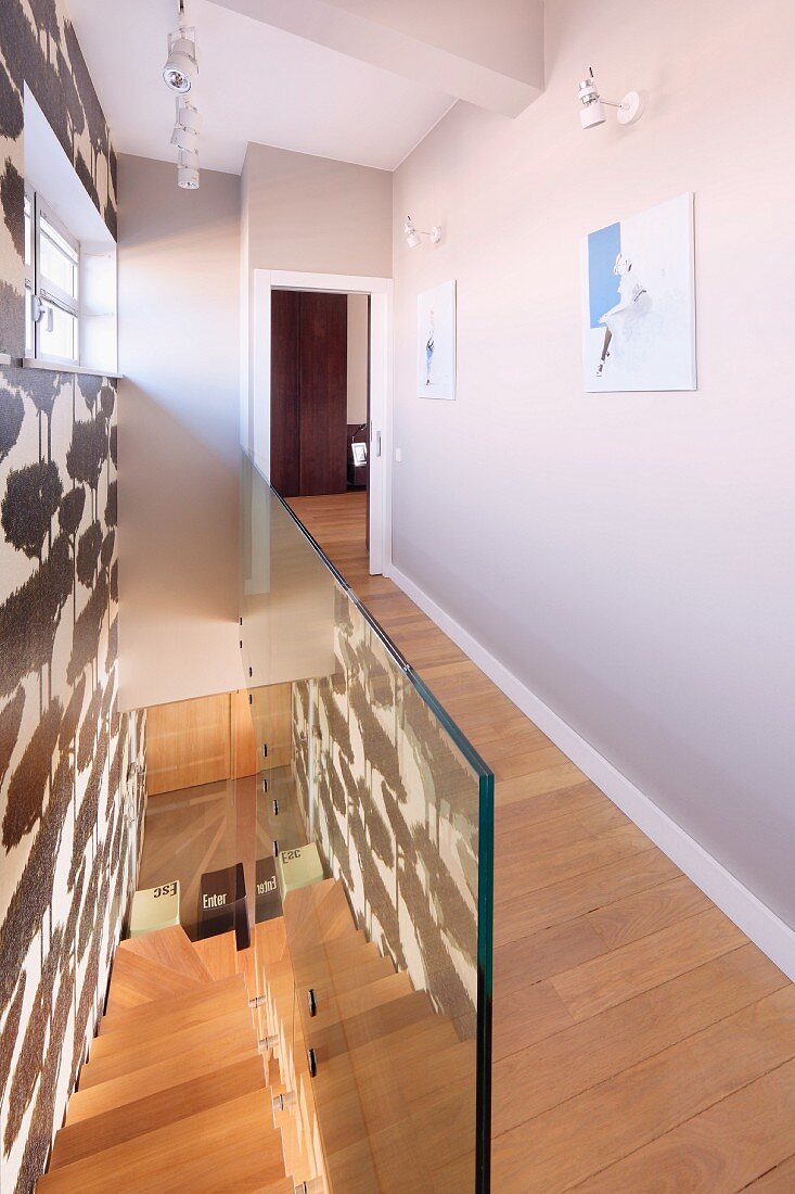 Wohnhaus mit modernem Treppenraum, schmaler Gang mit Dielenboden und Glasbrüstung vor Treppe