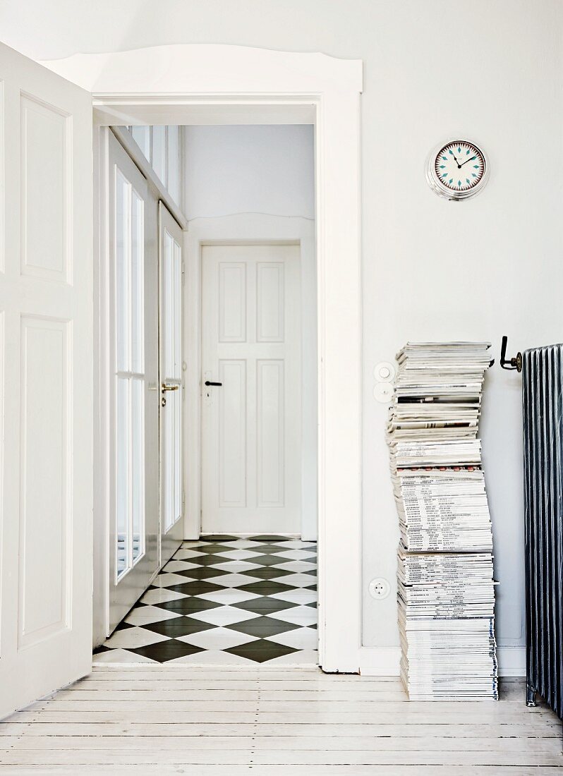 Zeitschriftenstapel neben offener Tür und Blick in Flur mit Schachbrettmusterboden, traditionelles Ambiente