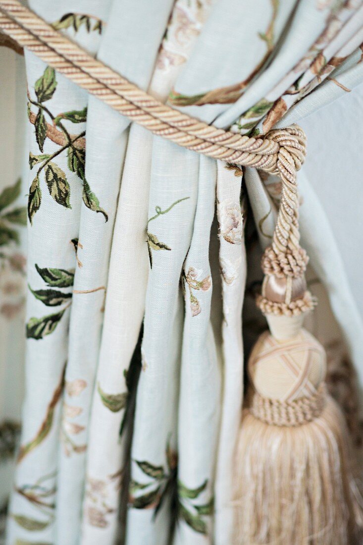 Curtain gathered with beige cord and tassel