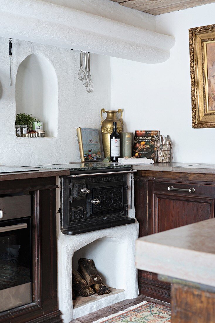 Alter gemauerter Ofen mit Holzlager in Küchenzeile integriert, darüber kleine Nische mit Rundbogen in Wand