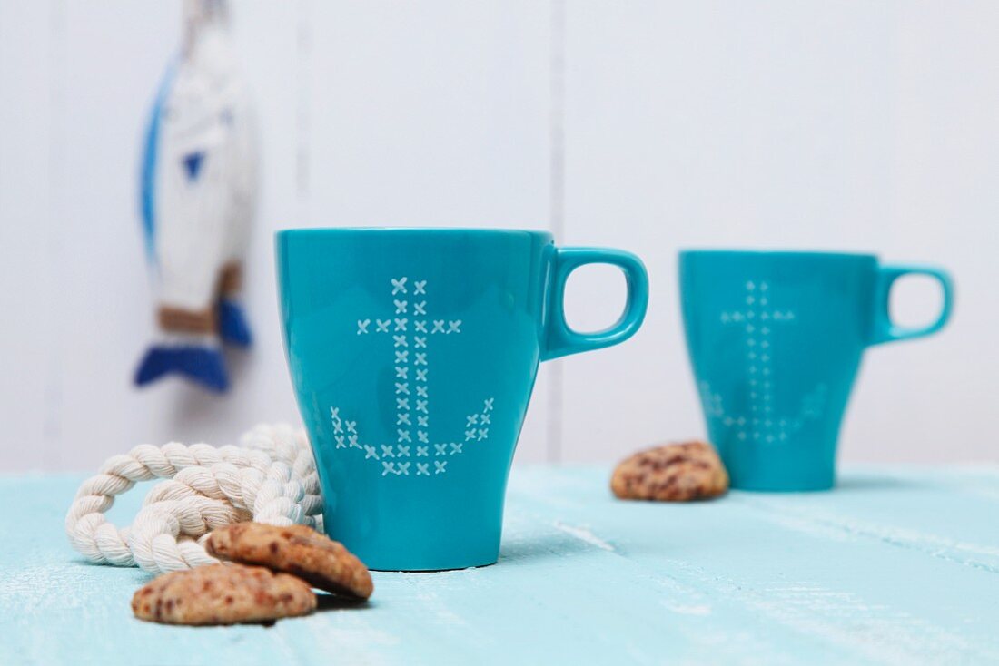 Blue mugs with anchor motifs in cross-stitch look
