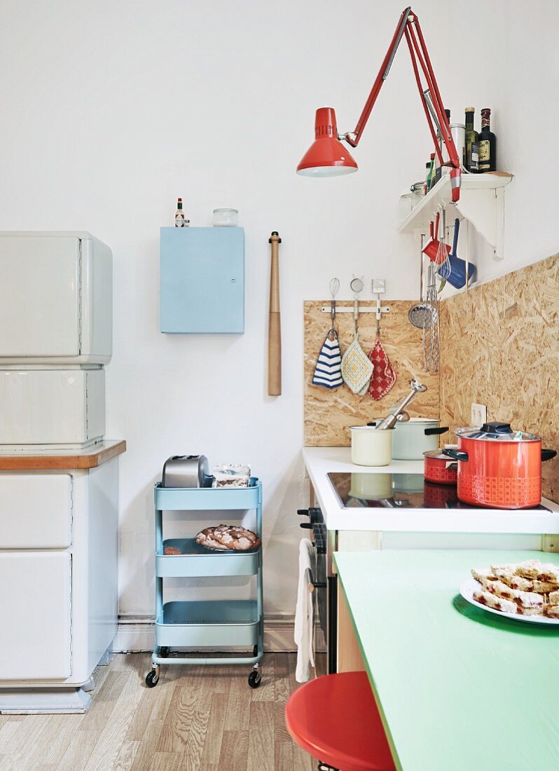 Fifties pastels paired with 70s orange in youthful, retro collectors' kitchen with old-fashioned kitchen dresser and DIY elements