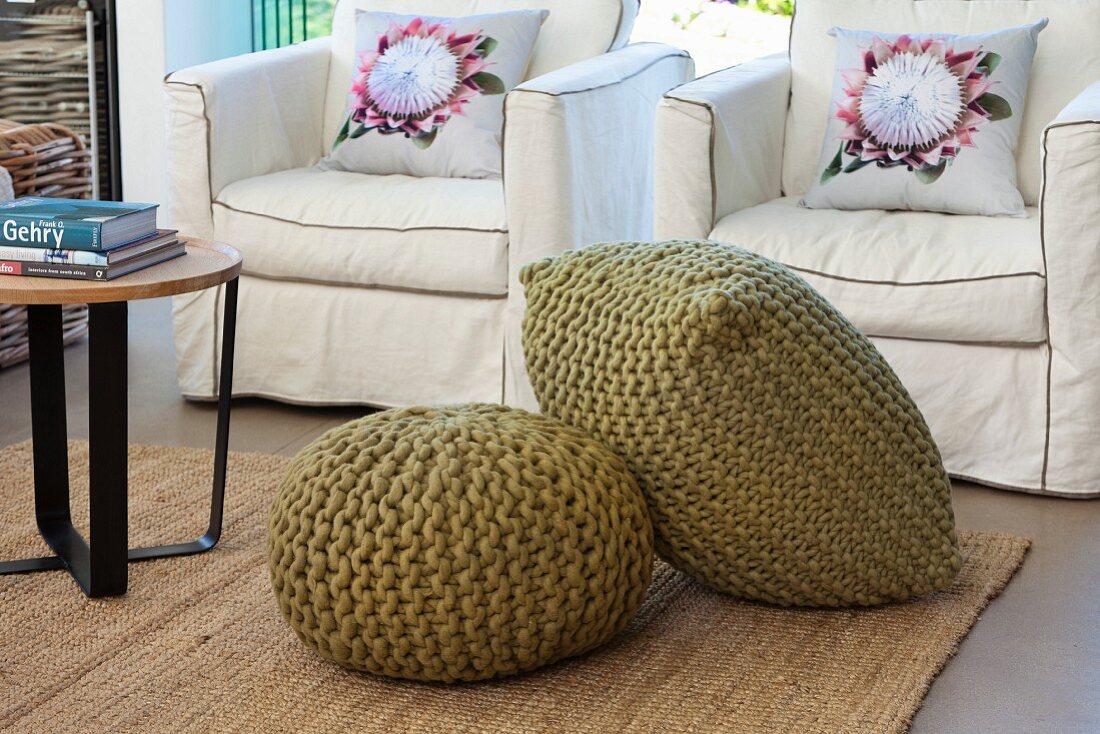 Olive-green pouffes in front of armchairs with washable loose covers and scatter cushions with floral motifs