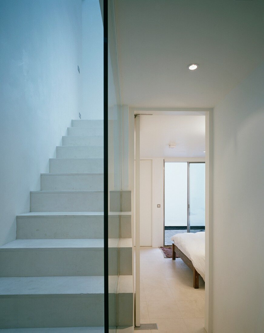 Weiß lackierte Treppe mit Glastrennwand und Blick durch offene Schlafzimmertür