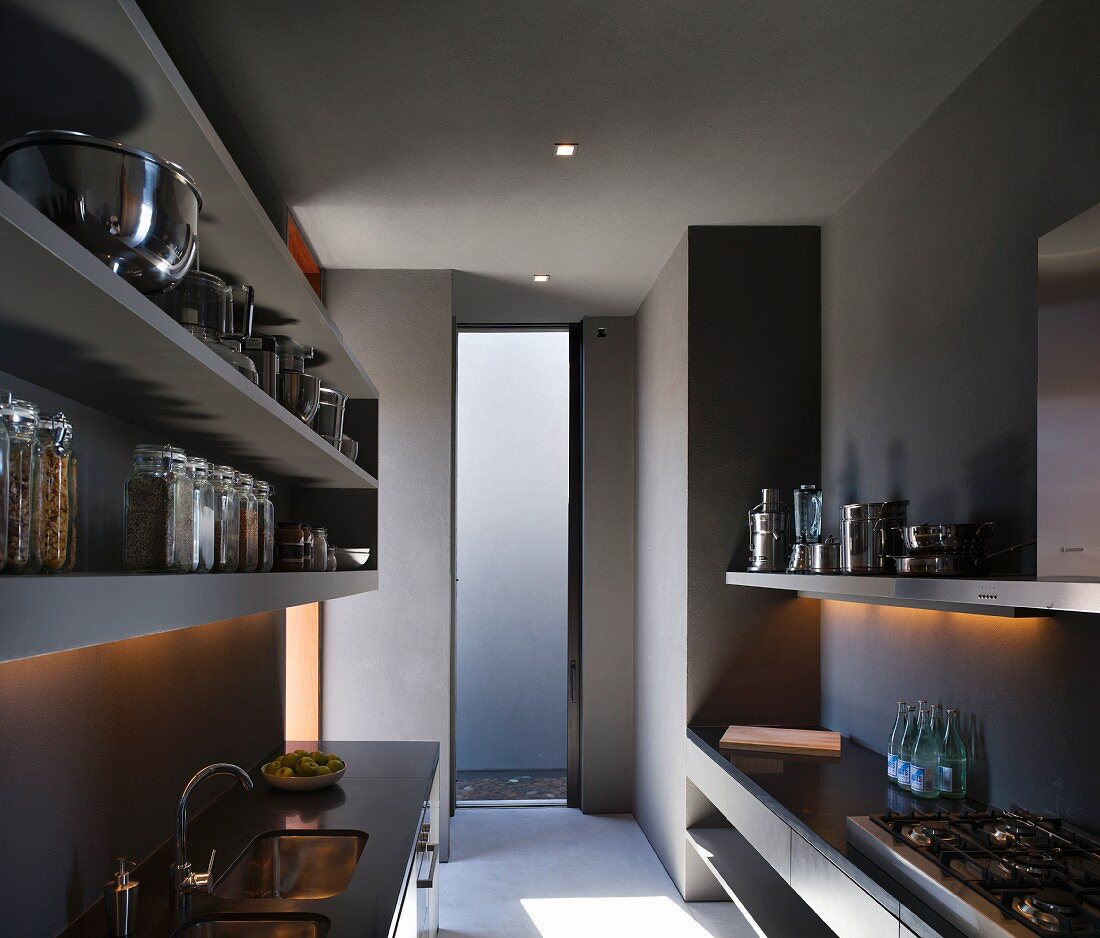 Graue, minimalistische Küche mit Unterbauspüle, Gasherd und schlichten Borden mit Edelstahl- und Glasgefässen