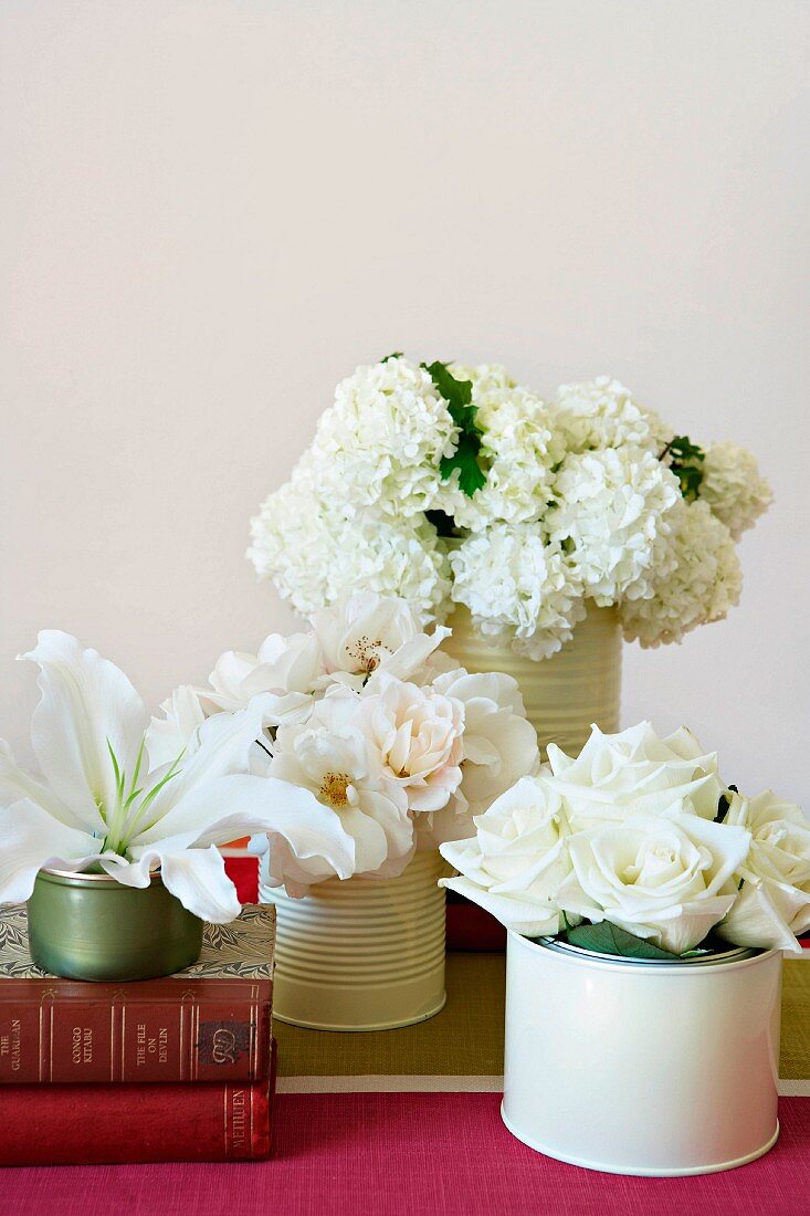 White hortensias, roses and lilies in tins