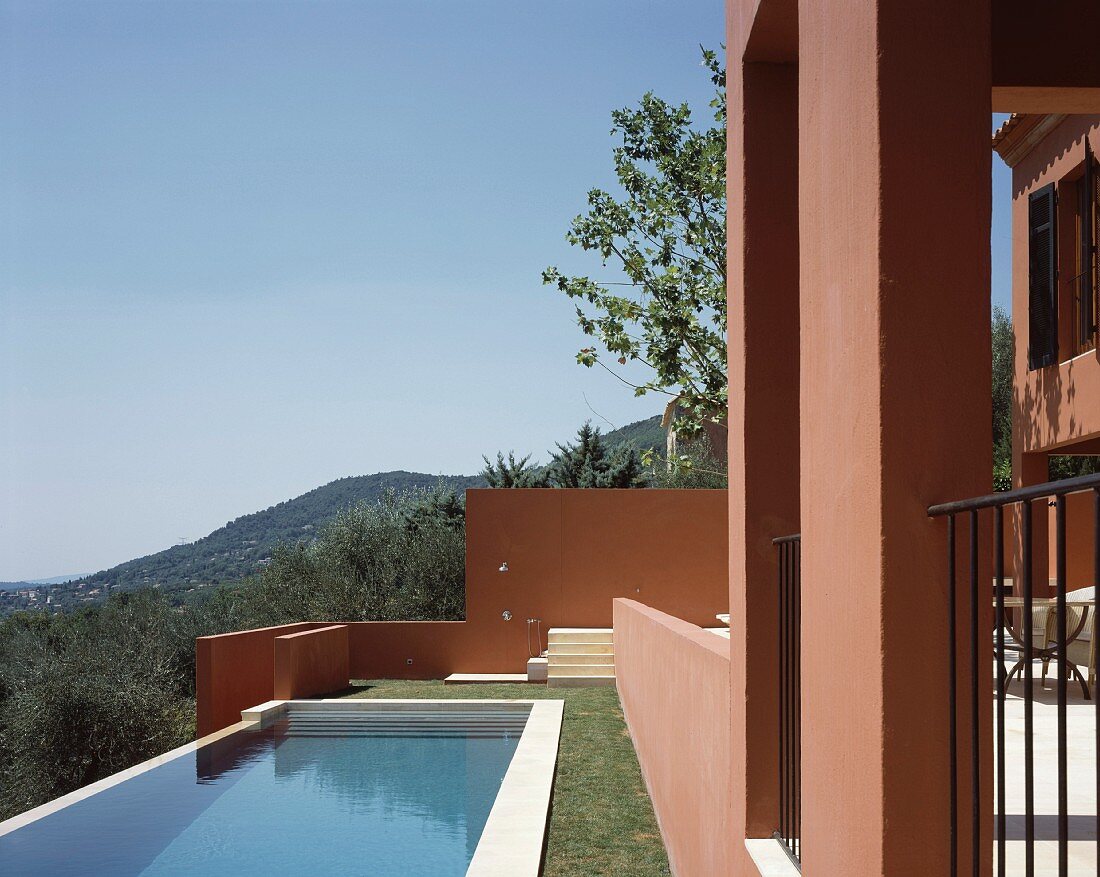Sonne über Pool im Garten und Mediterraner Wohnhaus mit rotbraun getönter Fassade