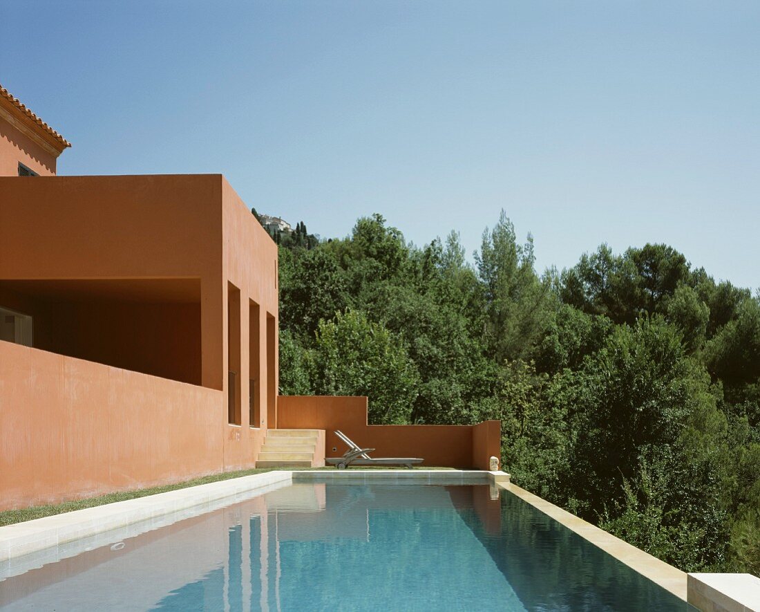 Vacation mood - by the pool in front of a Mediterranean home with a reddish brown facade