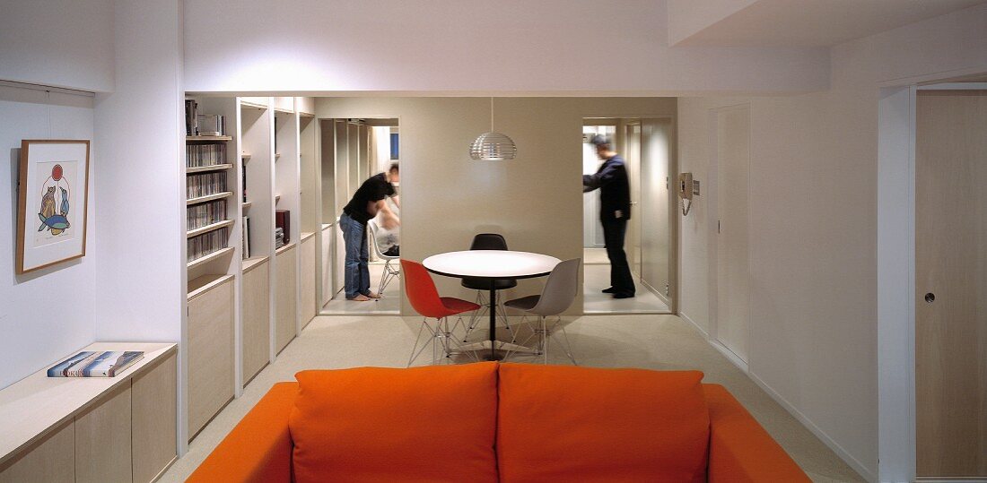 Orange sofa and bistro table with chair in Bauhaus style between two open hallways