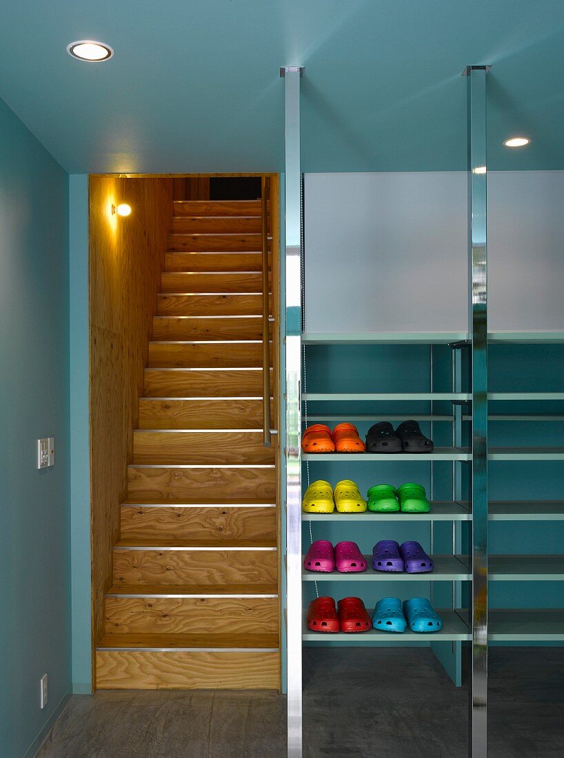Lobby with colorful plastic shoes in metal shelves next to a wooden staircase