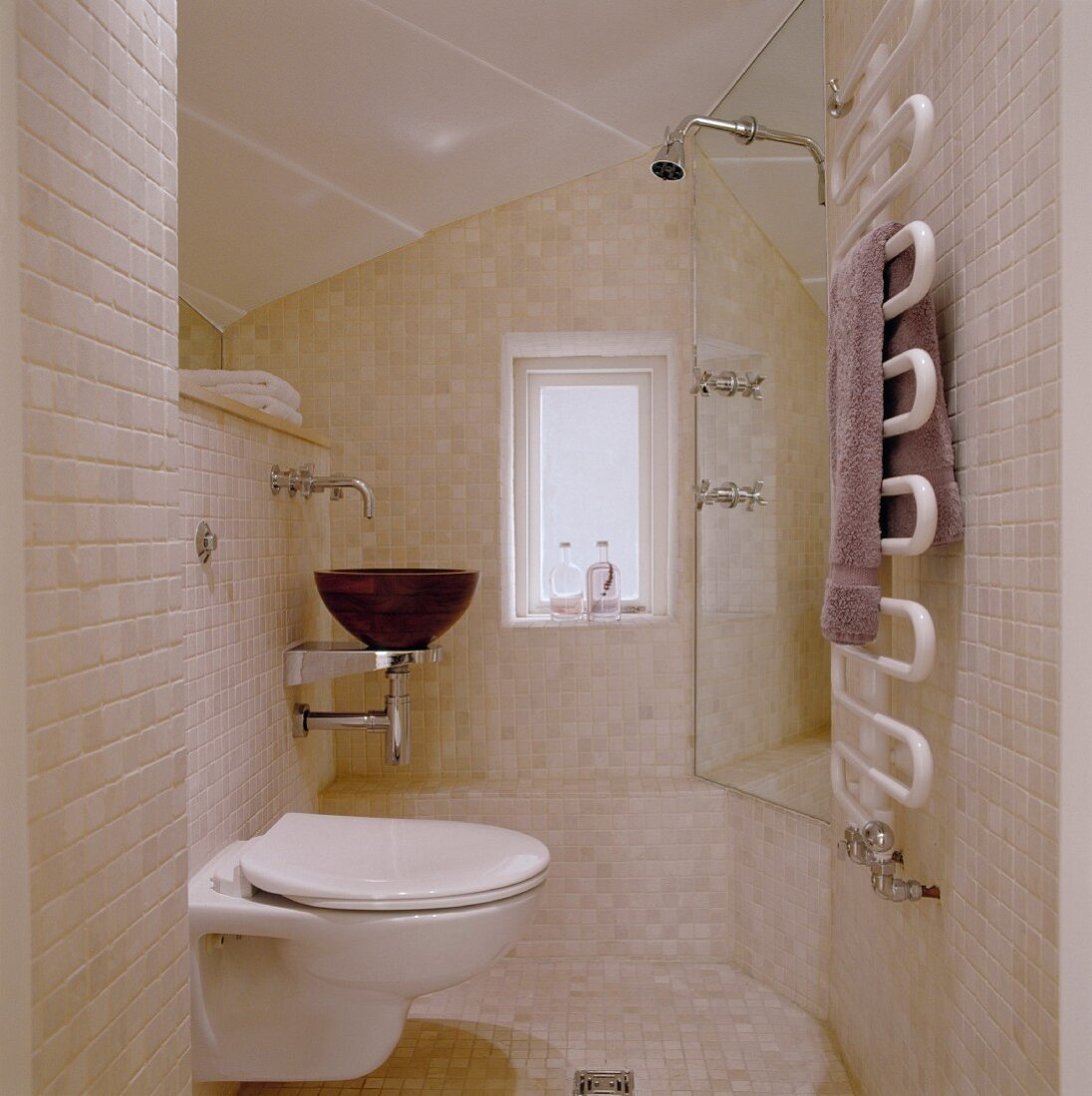 Gefliestes Bad mit hellen Wandfliesen und WC neben Waschtisch mit Waschschüssel aus Holz gegenüber der Duschkabine