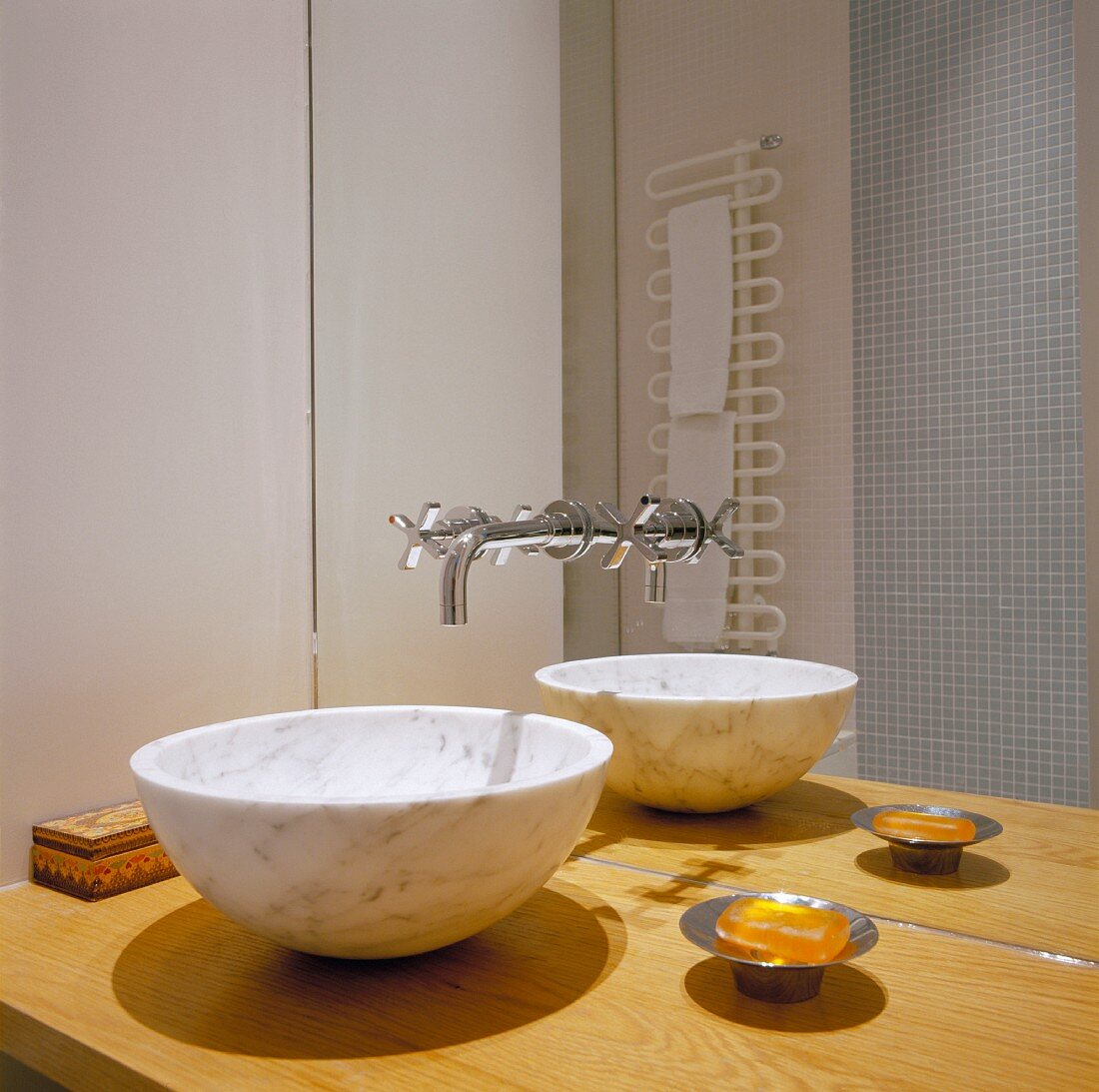 Waschschüssel aus Marmor auf Holzplatte und Designerarmatur an Spiegelwand