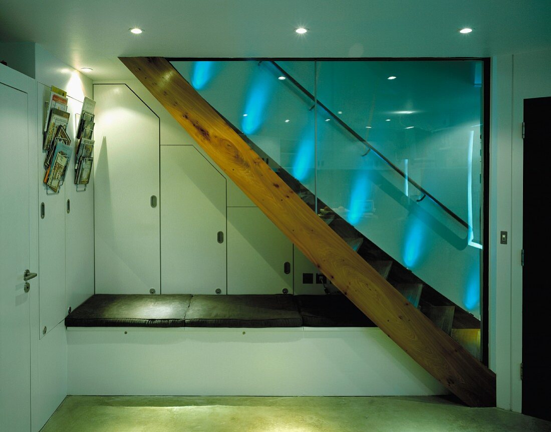 Holztreppe mit Glastrennwand und in Treppennische Sitzpolster auf Podest