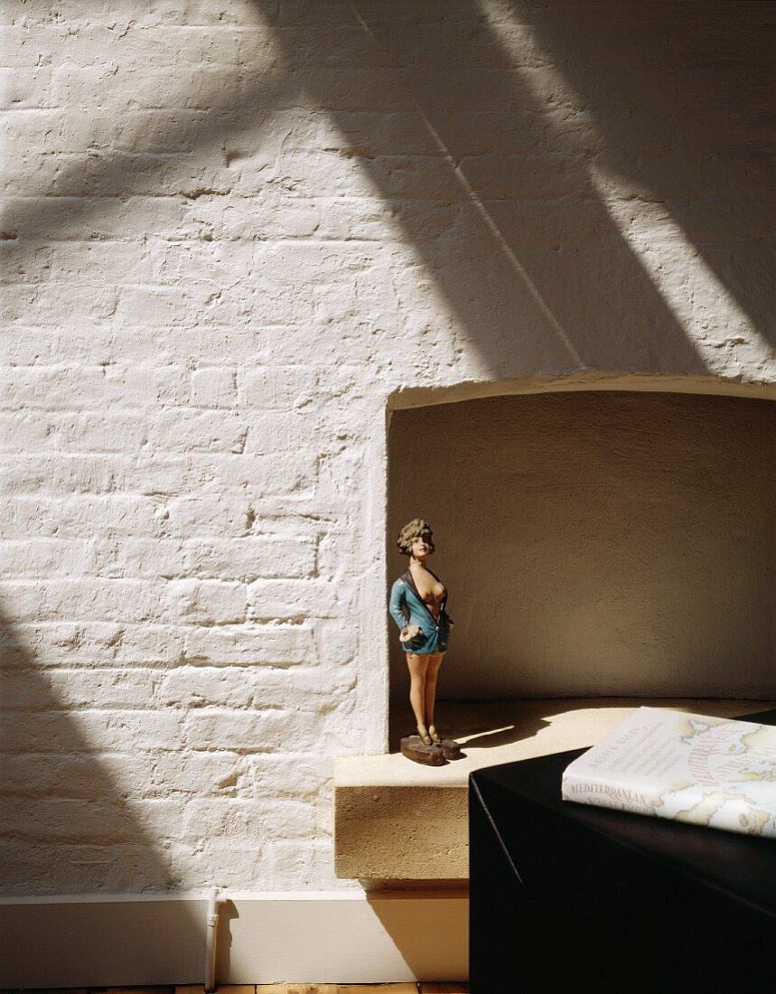 Doll in a former fireplace and whitewashed brick wall