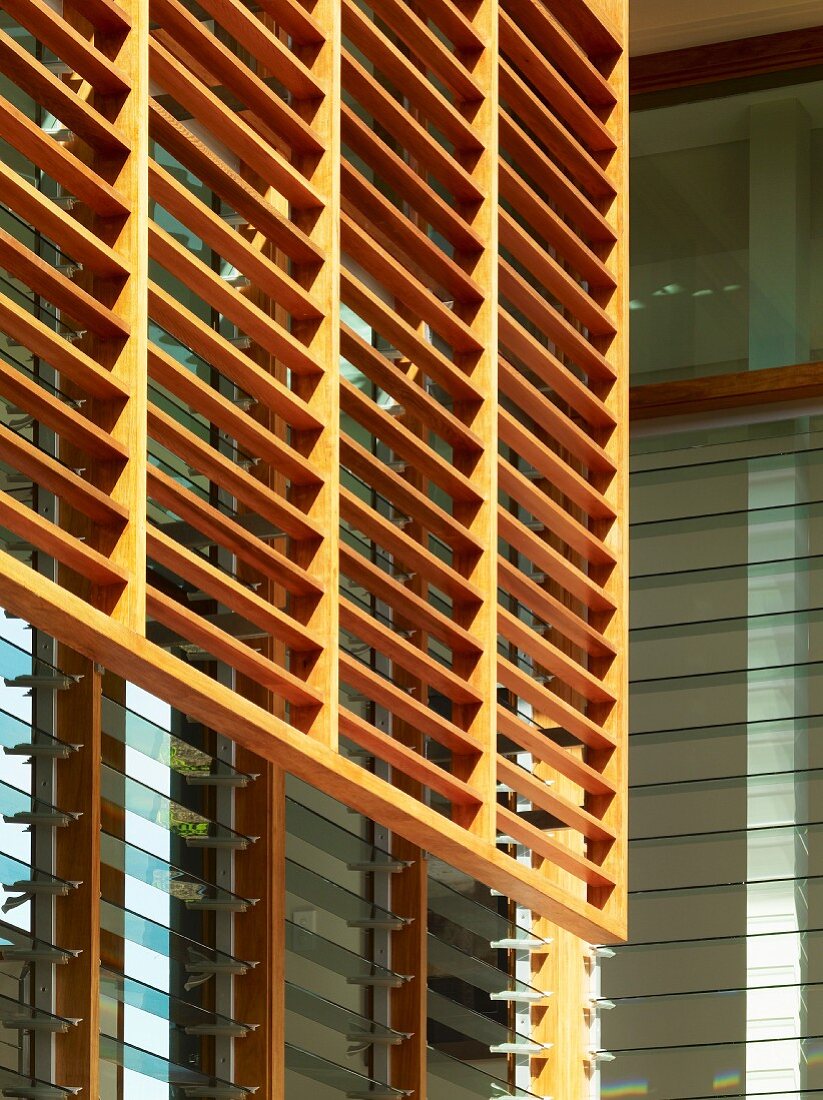 Wooden louvers in front of a house facade with adjustable glass louvers