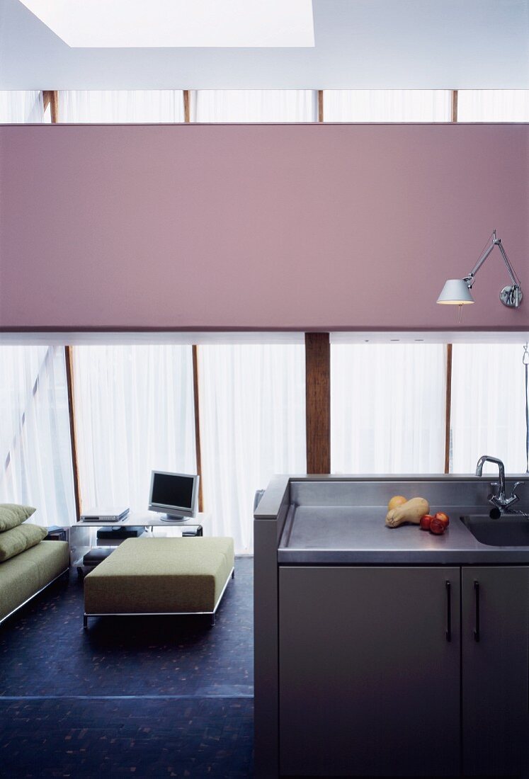 Küchenausschnitt mit Spüle und Blick in offenen modernen Wohnraum auf hellgrünen Polsterhocker