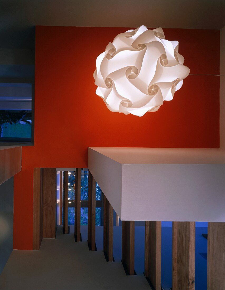 Designerlampe vor orangeroter Wand in moderner Eingangshalle