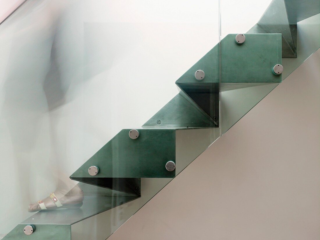 Side view of sculptural steel staircase with glass balustrade