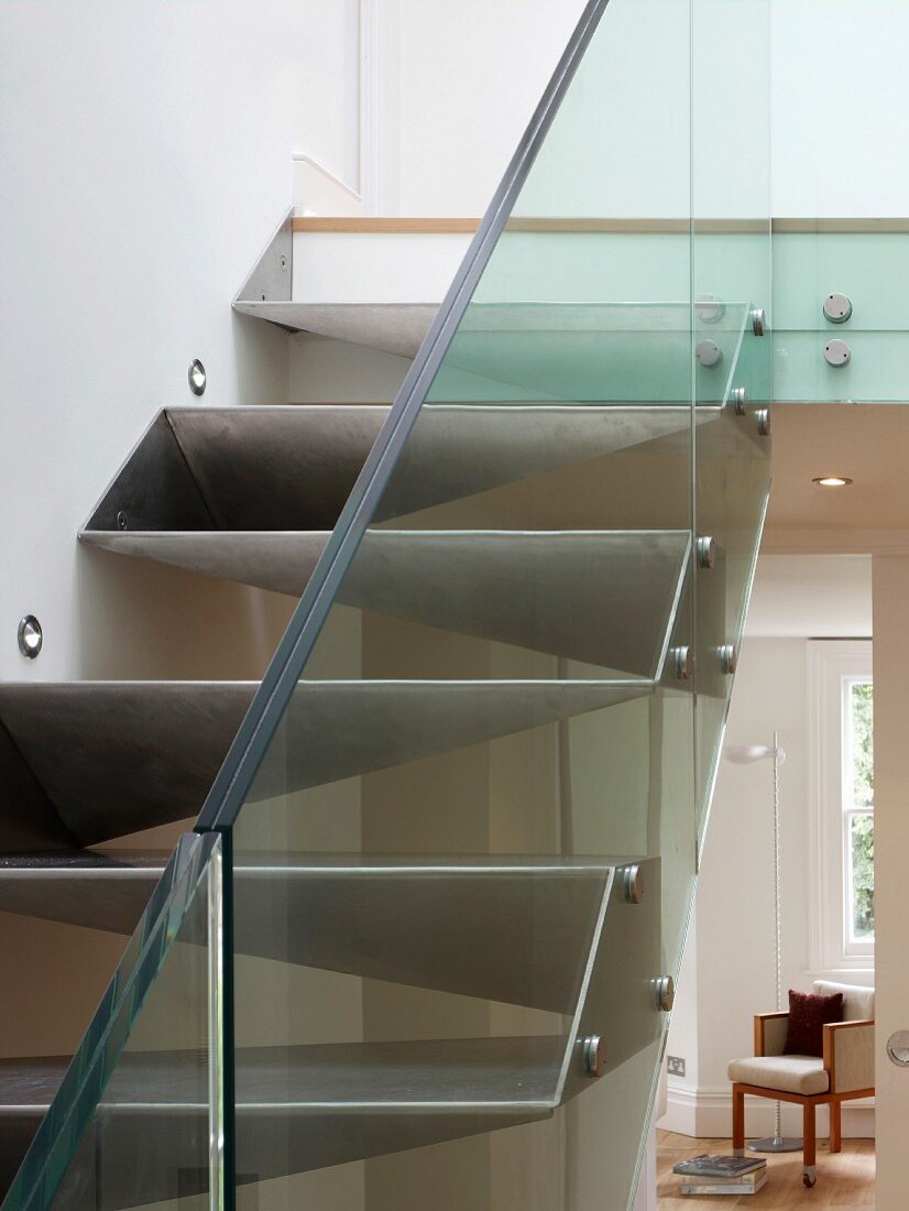 Ausschnitt einer massgefertigten Treppe aus Metall mit Glasgeländer und Blick durch offene Wohnzimmertür
