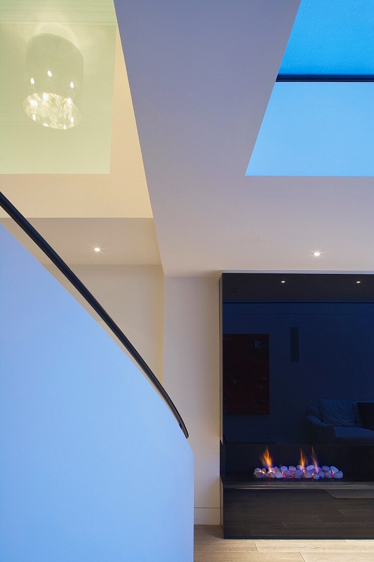 Detail of living room with balustrade and fireplace with black, reflective cladding