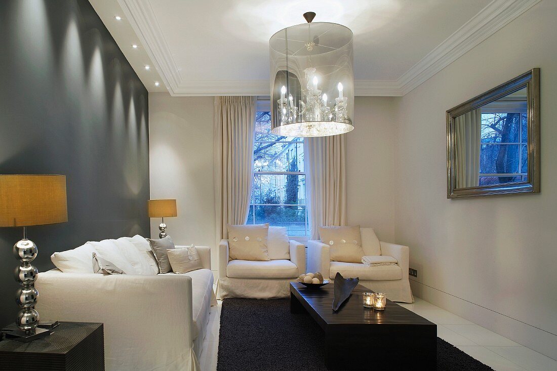 Elegant living room with upholstered seating and designer pendant lamps with shaded chandeliers