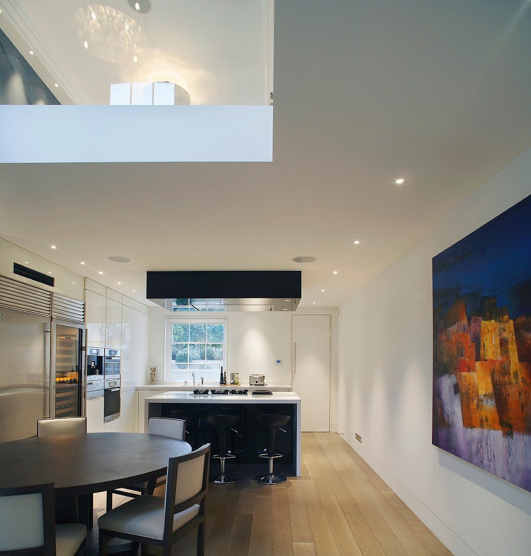 Dining area in front of designer kitchen counter and view of gallery through ceiling cut-out
