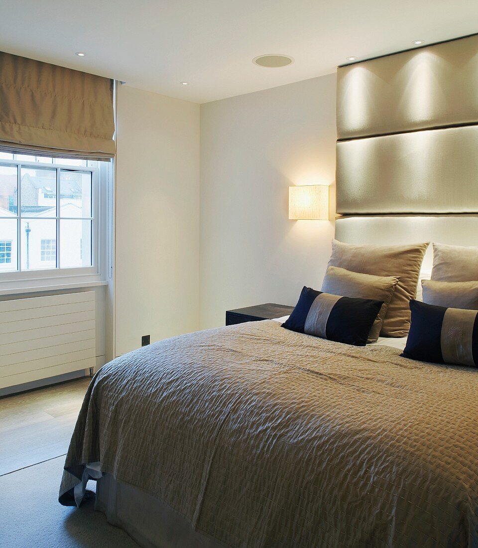 Double bed with ceiling-height upholstered head in modern bedroom