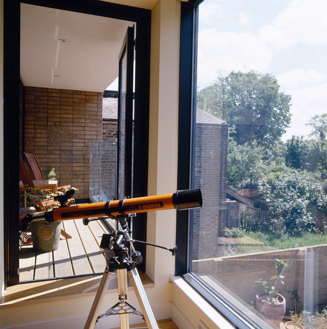 Telescope on a tripod in front of a large bank of windows