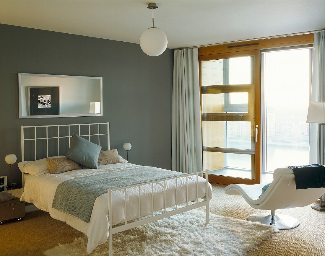 Schlafzimmer mit Doppelbett und modernem weißem Metallgestell vor grauer Wand