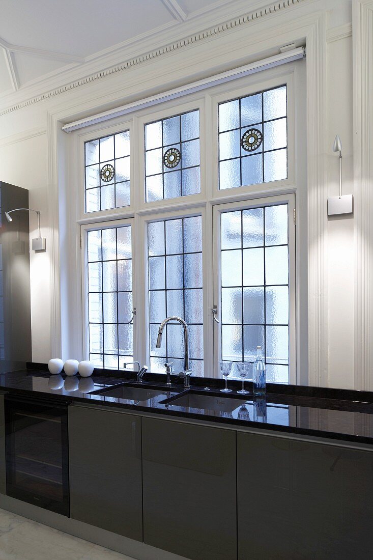 Designte Küchenzeile mit brauner Front und glänzender Arbeitsplatte vor Bleiglasfenster