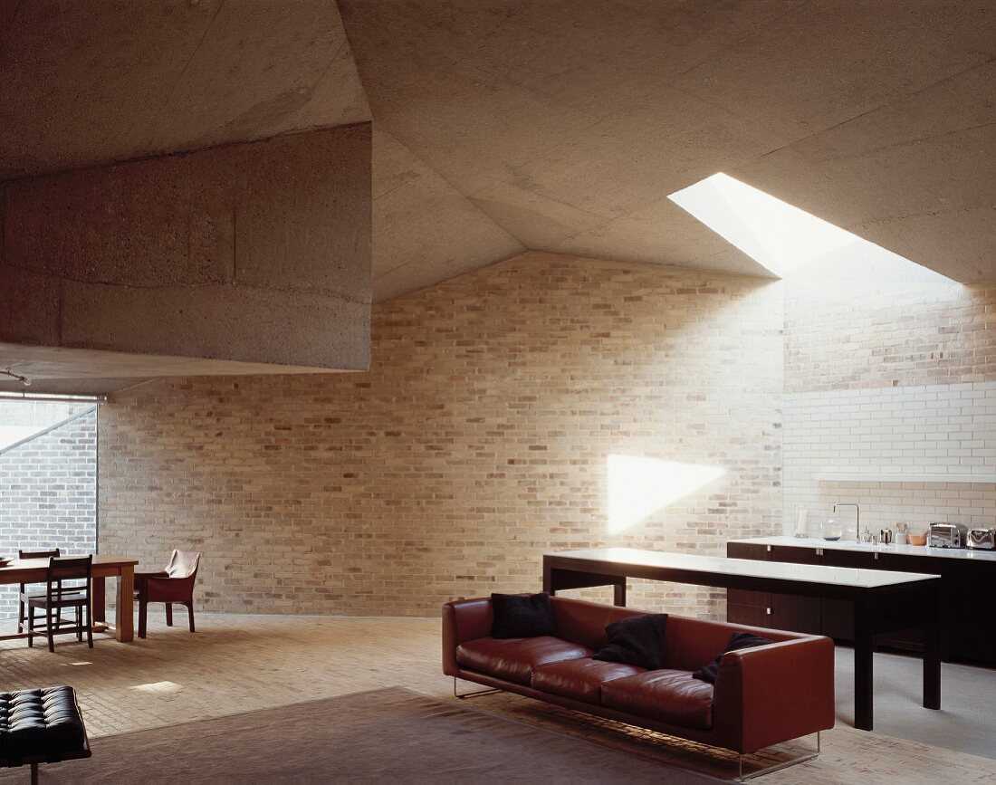 Braunes Ledersofa vor offener Küche im Wohnraum in futuristischer Architektur