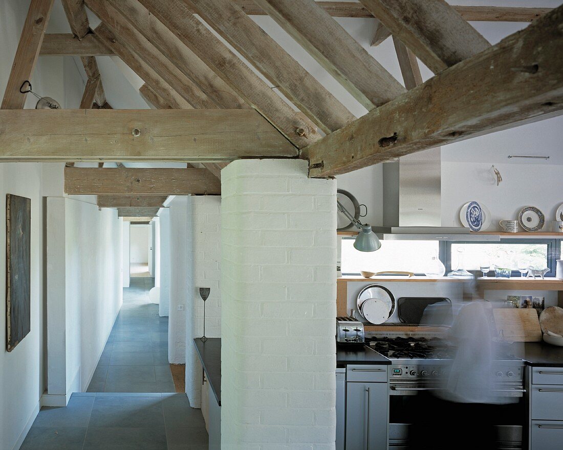 Langgestreckter Gang mit rustikaler Holzkonstruktion und Blick in offene Küche