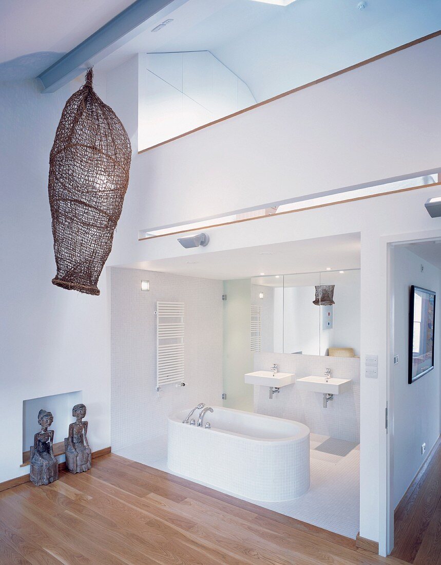 Open bath with a white freestanding bathtub under a gallery