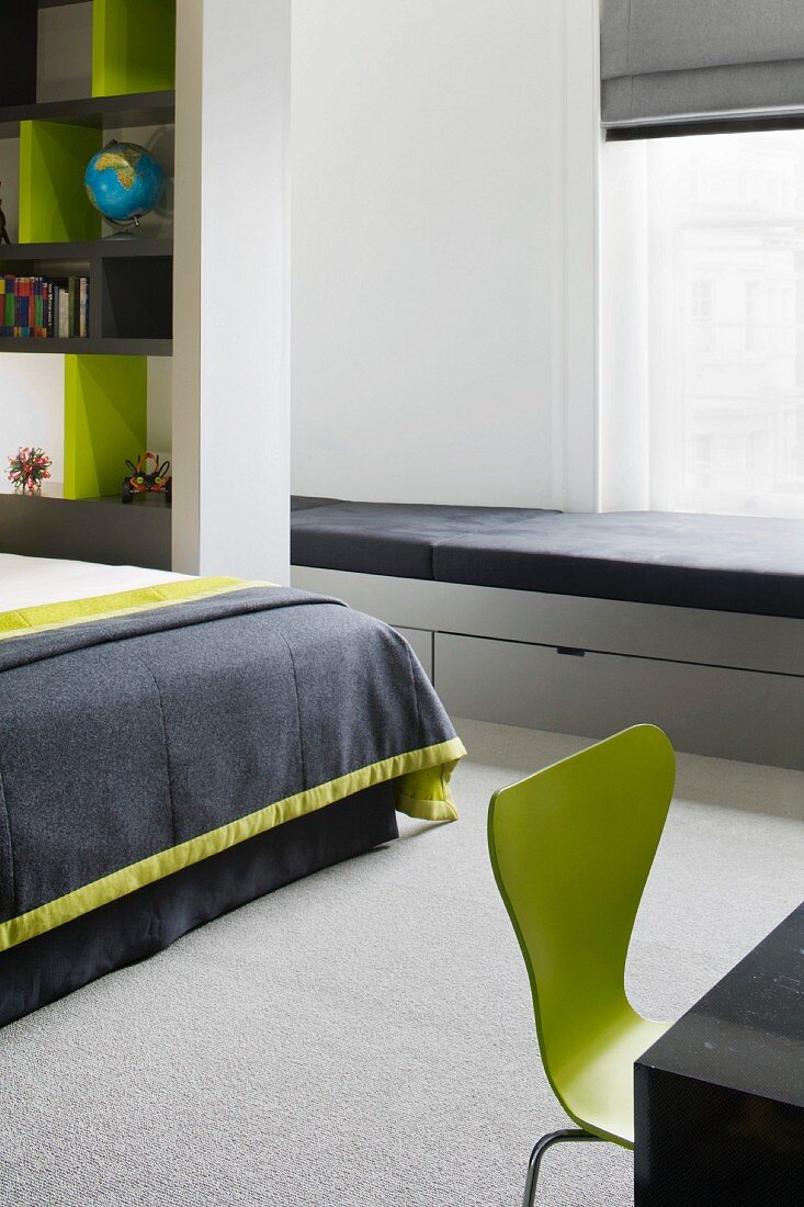 Hellgrau lackierte Sitzbank mit schwarzen Polstern und Schubladen im modernem Schlafraum mit grünem Retrostuhl