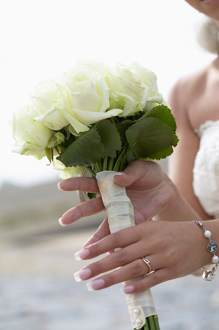 A bride holding a small bunch of white roses