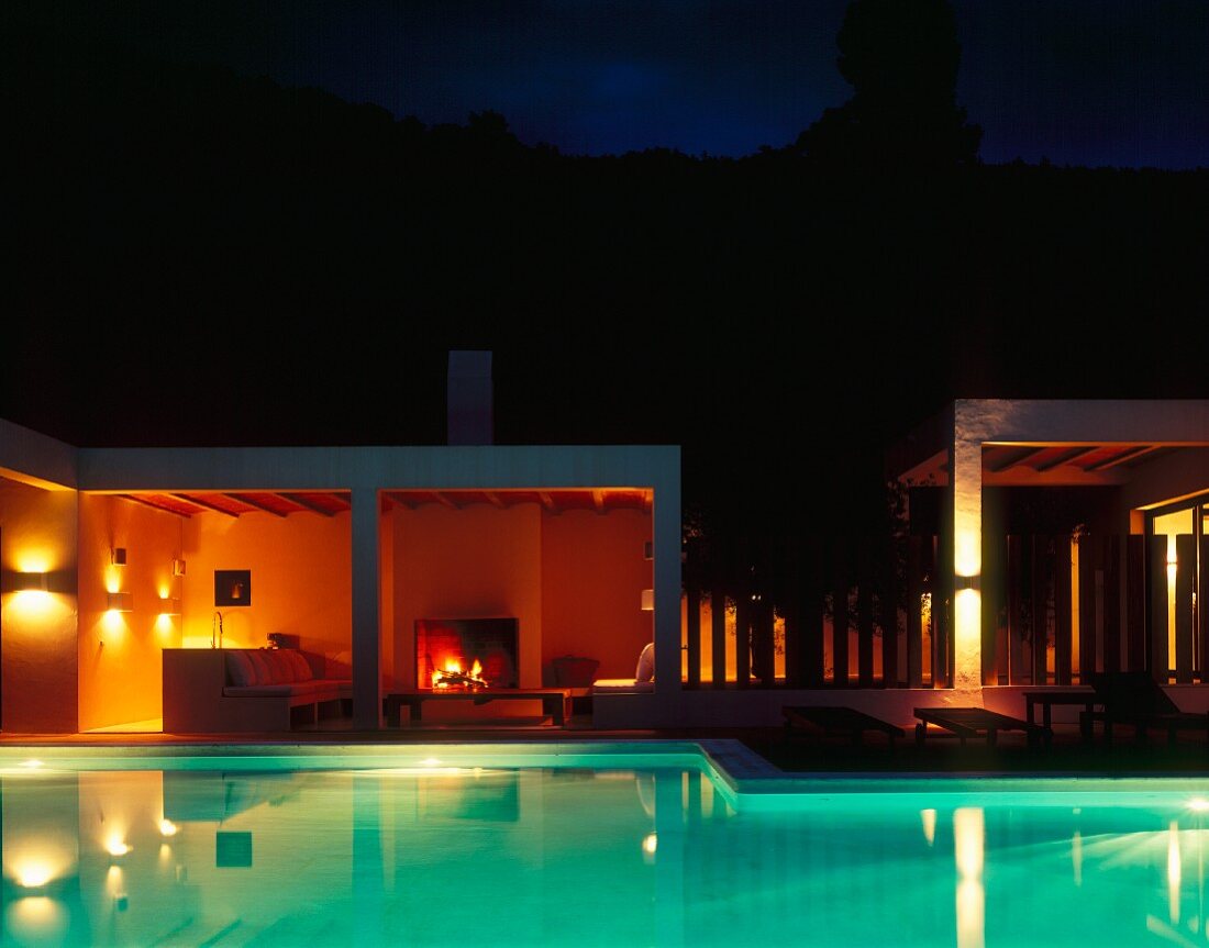 Nachtstimmung am Pool mit Unterwasserbeleuchtung und Kaminfeuer auf Terrasse