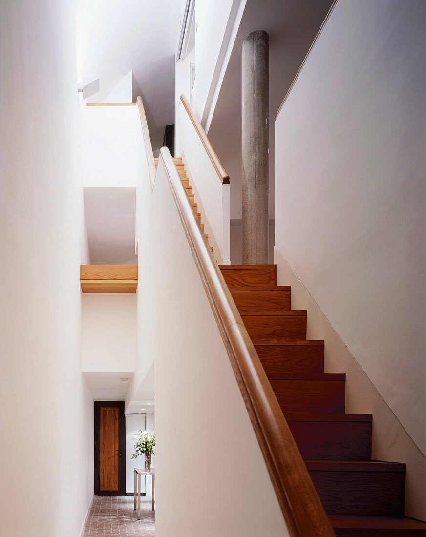 Weisses Treppenhaus mit Luftraum und mehrstöckiger Holztreppe
