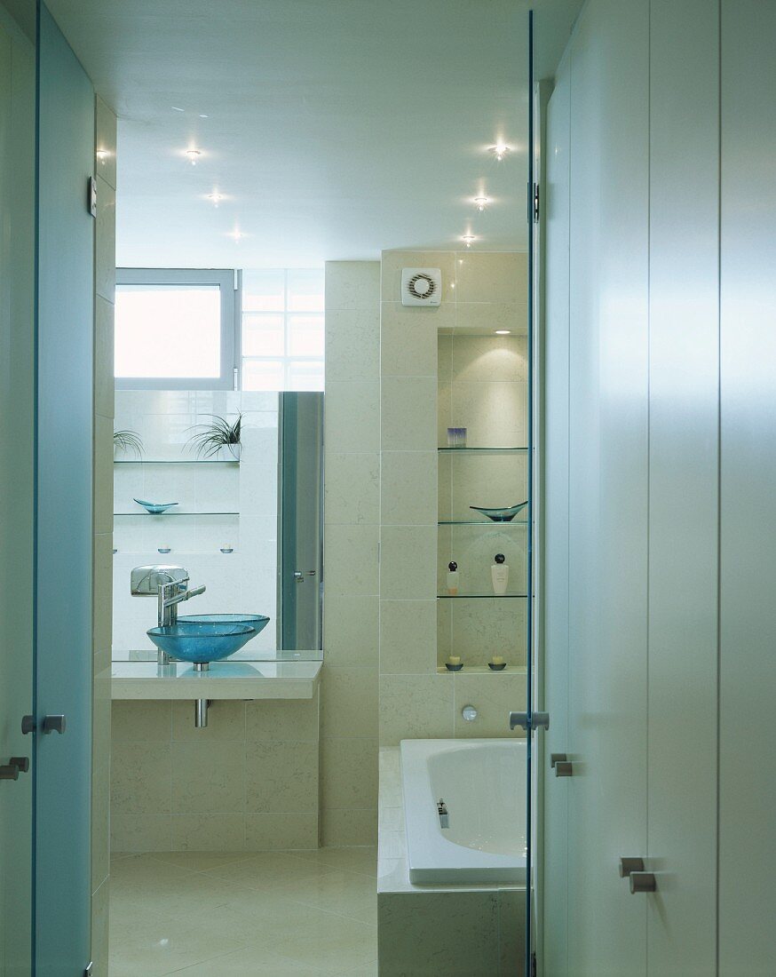 White built-in cupboards in front of an open bathroom door with a view of the bathtub and vanity