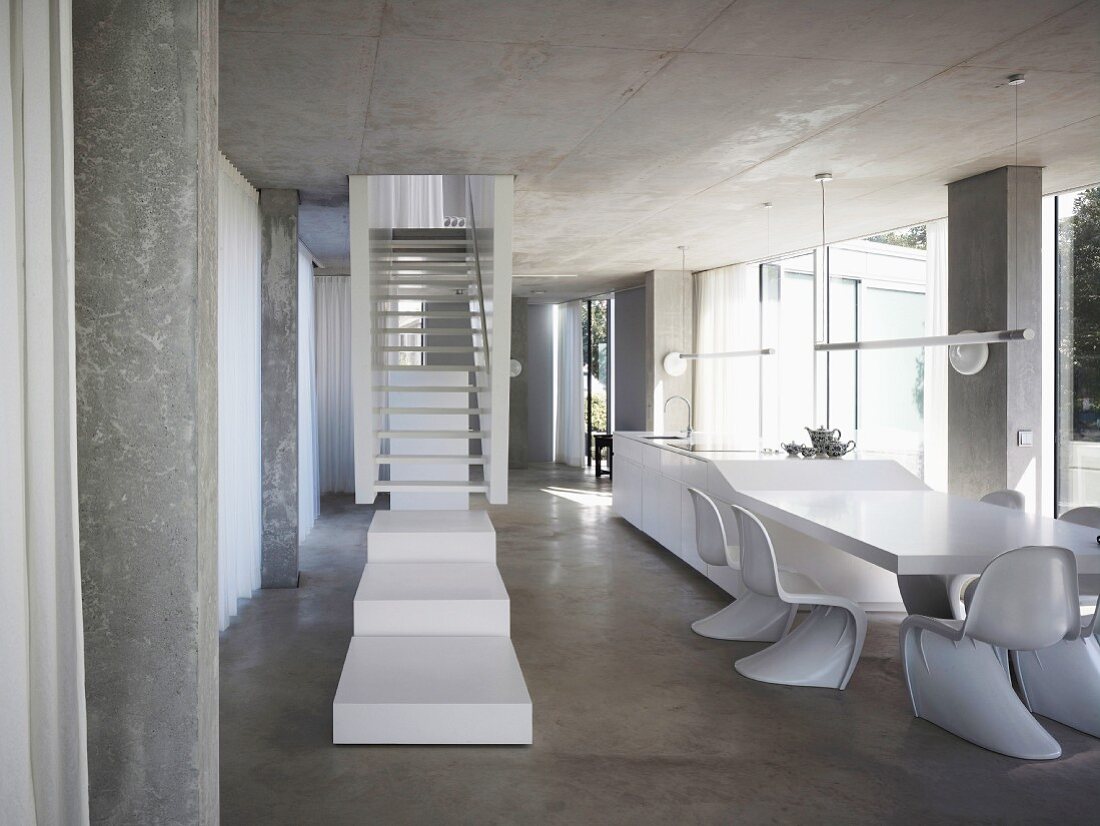 Weisses Treppenpodest vor Treppe im offenen Wohnraum mit Schalenstühlen aus Bauhauszeit vor Esstisch